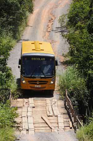 Ônibus escolar atravessa uma ponte de madeira refeita após desabar com caminhão: tábuas soltas e guard rail quebrado (Ronaldo de Oliveira/CB/D.A Press)