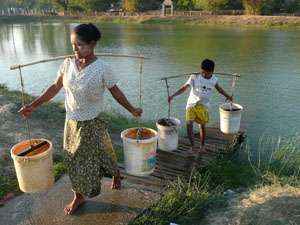 Criança ajuda mãe a retirar água de lago em Yangon, Mianmar:  (KHIN MAUNG WIN)