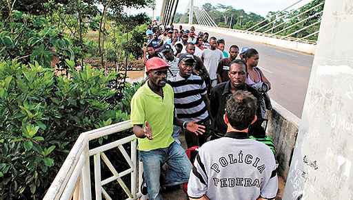 Policial federal impede a entrada de haitianos na ponte sobre o Rio Acre: só ingessa no país quem tem visto