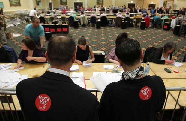 Trabalhadores são observados por fiscais enquanto contam votos do referendo