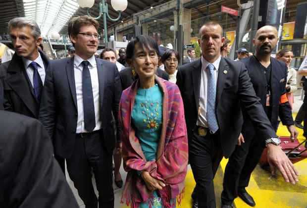 Suu Kyi é acompanhada por seguranças e pelo ministro francês do Desenvolvimento, Pascal Canfin, na chegada à Estação Ferroviária Gare du Nord