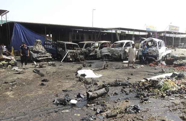 Moradores observam local de um atentado a carros-bomba em Kerbala