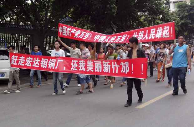 Moradores locais marcham com bandeiras durante protesto ao longo de uma rua em Shifang