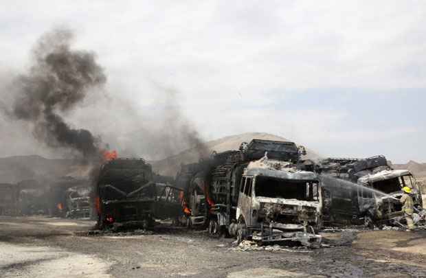 Bombeiro apaga fogo de caminhão destruído