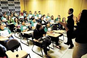 Em vez de voltarem os olhares para o professor, alunos prestam atenção à intérprete, que fica no canto da sala