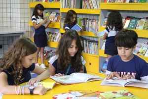 Giovana Smidt, Maria Eduarda Verano e Pedro Henrique Leal apreciam os novos livros da biblioteca: acervo renovado para se adequar à nova ortografia