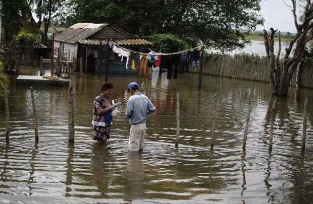 Mulher recebe mantimentos entregues por um homem no próprio quintal, alagado em decorrência da passagem do furacão Sandy