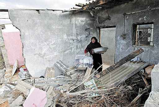 Mulher palestina observa o que restou de sua casa na Faixa de Gaza depois de ataque feito com mísseis israelenses