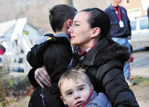 Em lágrimas, mãe abraça os dois filhos, depois de prestar sua homenagem às vítimas do massacre de Newtown