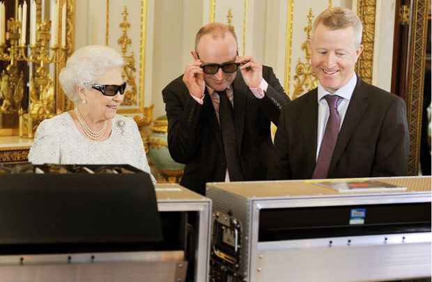 Rainha Elizabeth II, o produtor de tevê John McAndrew (C) e o diretor John Bennett assistem à gravação da mensagem