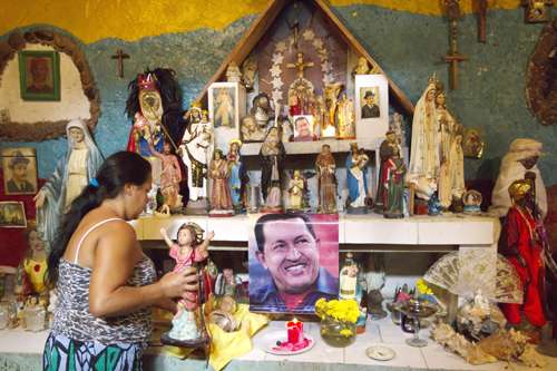 Moradora de Caracas observa o retrato do presidente Hugo Chávez, em meio a vários símbolos religiosos, em altar de igreja: pedido de milagre