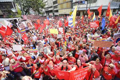 Fotos do presidente e a imagem de Cristo se misturam ao vermelho da multidão, em Caracas: 