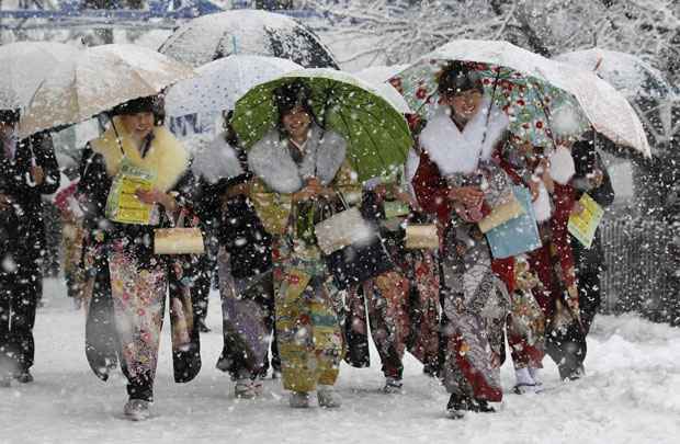 Mulheres japonesas caminham durante a forte nevasca para assistir a evento cerimonial em Toshimaen, parque localizado na capital