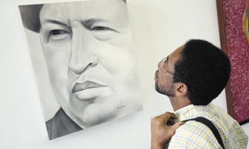 Venezuelano observa quadro da exposição Chávez vive e vencerá, em Caracas: presidente há 39 dias hospitalizado em Havana