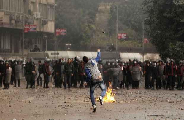 Manifestante atira pedras contra policiais em confronto próximo à Praça Tahrir