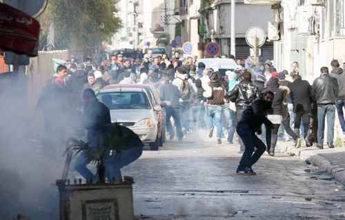 Manifestantes tentam se proteger da fumaça de gás lacrimogêneo durante confrontos com as forças de segurança, perto do prédio do Ministério do Interior, no centro de Túnis: assassinato de opositor detonou a nova crise