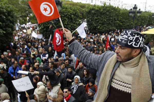 Os manifestantes gritam palavras de ordem e agitam a bandeira nacional durante uma manifestação de apoio ao partido Ennahda em Tunis