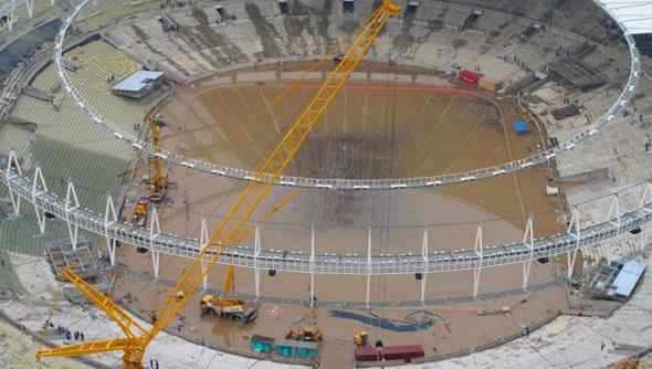 Funcionários da obra trabalhavam para esvaziar a grande poça que se formou sobre a lona que está sendo instalada na cobertura do estádio