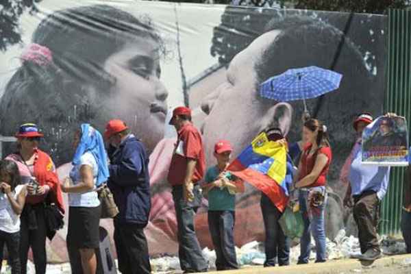 Diante de uma imagem do presidente, venezuelanos fazem fila para ver o corpo embalsamado: 