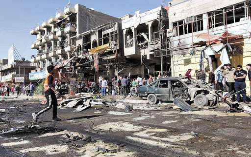 Moradores do bairro de Al-Mashtal, em Bagdá, observam os destroços de carro-bomba, após uma das explosões que atingiram civis xiitas