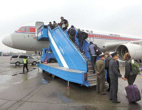 Oficial norte-coreano checa passaportes de grupo de diplomatas estrangeiros e de turistas que embarcou no voo da Air Koryo, rumo a Pequim, no aeroporto de Pyongyang