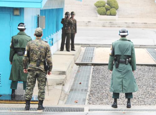 Soldado norte-coreano usa binóculo (ao fundo) para observar militares sul-coreanos, no vilarejo fronteiriço de Panmunjom, na Zona Desmilitarizada