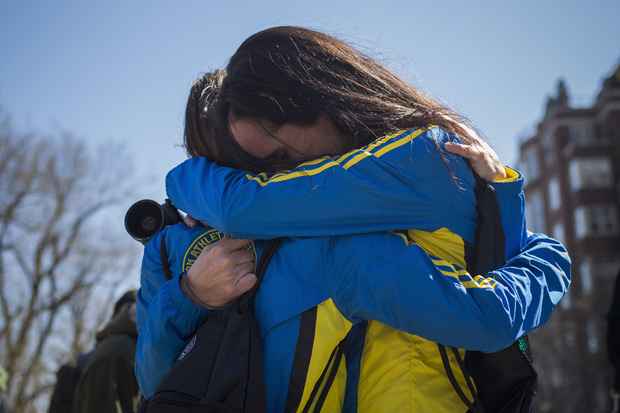 Corredoras Lisa Kresky-Griffin e Tammy Snyder (D) se abraçam na entrada da barricado na Boylston Street, perto da linha de chegada da Maratona de Boston, em Boston, Massachusetts