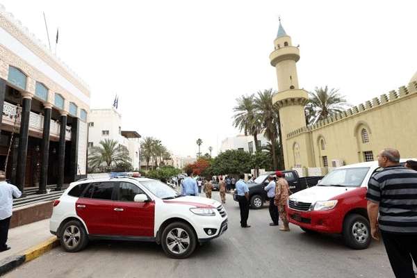 As forças de segurança líbias e os moradores se reúnem na rua das embaixadas da Argélia, Grécia e Arábia, onde uma bomba explodiu levemente prejudicando um carro em 18 maio, em Tripoli. Uma fonte de segurança disse que a bomba de fabricação caseira, conhecida localmente como 