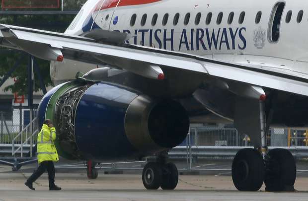 Trabalhador passa por avião de passageiros da British Airways depois que foi rebocado para fora da pista após pouso de emergência no Aeroporto de Heathrow