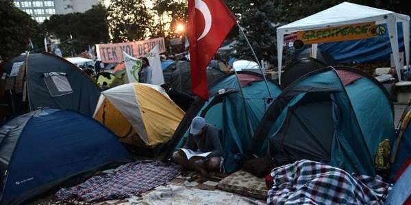 Um manifestante lê uma revista, entre barracas em Gazi parque junto à Praça Taksim, em Istambul