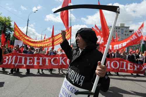 Um manifestante segura uma foice enquanto pessoas marcham ao longo de uma rua durante um protesto da oposição de Putin no centro de Moscou