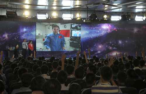 Os alunos levantam as mãos para fazer perguntas para Wang Yaping (na tela),a astronauta do grupo de uma nave espacial que dá uma palestra em uma escola em Beijing