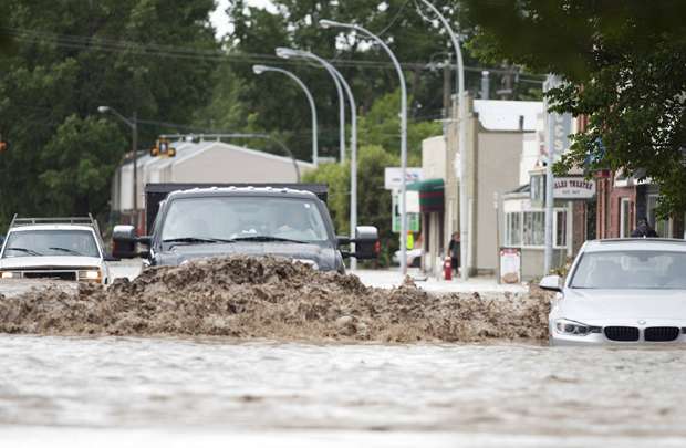 Carros trafegam por enchentes no centro de High River em Alberta, no Canadá