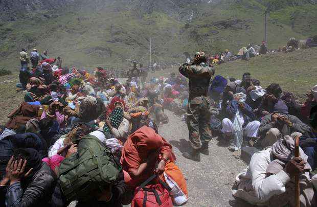 Moradores e soldados cobrem os rostos por causa das terras espalhadas por helicóptero durante as operações de resgate em Badrinath, no estado do Himalaia