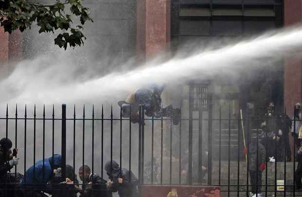 Estudante cai cerca que ele estava subindo, após ser atingido por jato de água jogado pela polícia de choque durante protesto contra o governo em Santiago