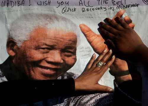 Mulheres tocam faixa com foto de Nelson Mandela do lado de fora da Medi Clinic Hospital do Coração, em Pretória, onde o ex-presidente da África do Sul está hospitalizado