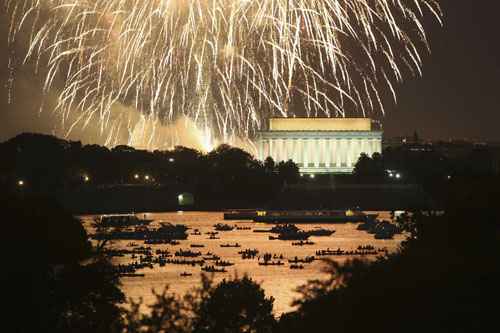 Pessoas assistem a partir de barcos no rio Potomac, fogos de artifício do Dia da Independência iluminar o céu sobre Washington