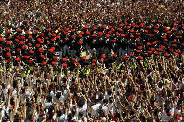 Banda de música municipal de Pamplona passa por foliões na praça da Câmara Municipal no início do Festival de São Fermino