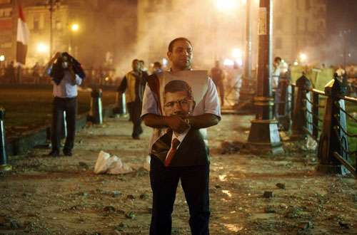 Um defensor de Mohamed Morsy abraça um cartaz com a foto do presidente deposto durante confrontos com a polícia e manifestantes anti-Morsy no centro do Cairo