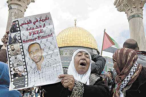 Manifestante exibe cartaz com foto de prisioneiro palestino, diante da Mesquita de Al-Aqsa, em Jerusalém