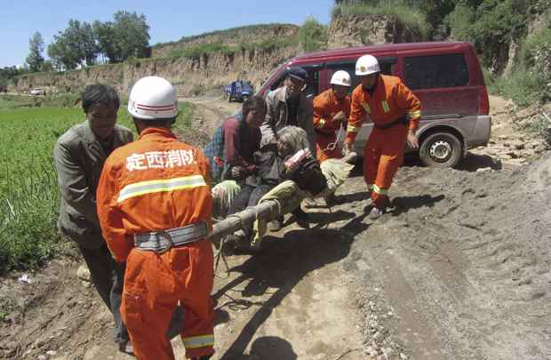 Bombeiros carregam mulher ferida em maca após terremoto de magnitude 6,6 na província de Gansu