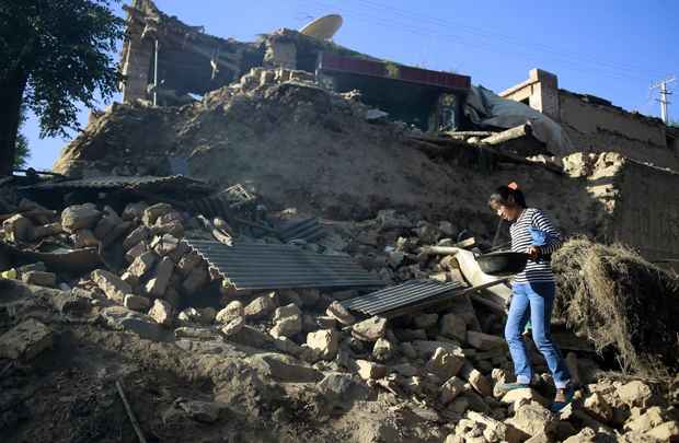 Mulher segura panela que conseguiu recuperar de casa que desabou após o terremoto