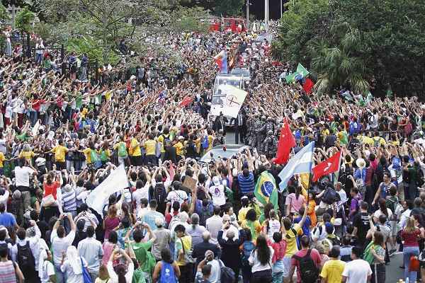 Com os vidros do carro aberto e sempre acenando para os fiéis