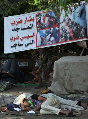 Partidário do presidente deposto Mohamed Mursi dorme sob uma bandeira anti-exército próximo a Universidade do Cairo