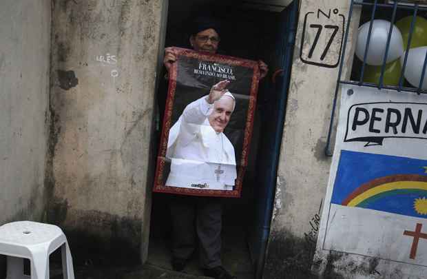 Morador da favela Varginha mostra cartaz de papa Francisco momentos antes do pontífice chegar na comunidade do Rio de Janeiro