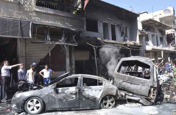 Pessoas se reúnem em torno de destroços depois que carro-bomba explodiu no distrito de Jaramana, sudeste Damasco