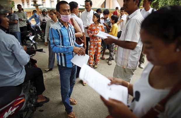 Pessoas leem cartilha distribuída pela oposição depois de rejeitar os resultados das eleições em um templo budista, em Phnom Penh