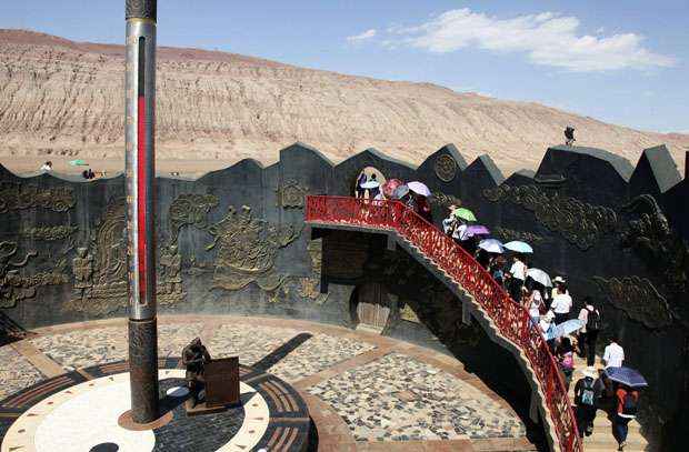 Turistas chineses caminham pela Montanha Flamejante em Turpan: o termômetro de 12m de altura mostra que a superfície da região atingiu 78°C