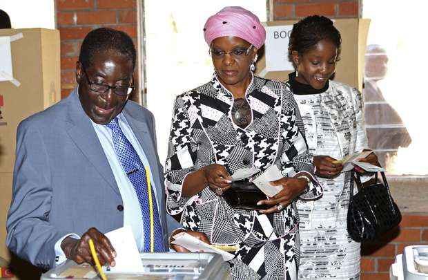 O presidente do Zimbábue, Robert Mugabe lança voto em urna acompanhado da esposa e da filha em Harare