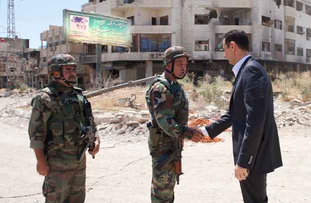 Bashar al-Assad (D) aperta a mão de militar militar durante visita a Daraya